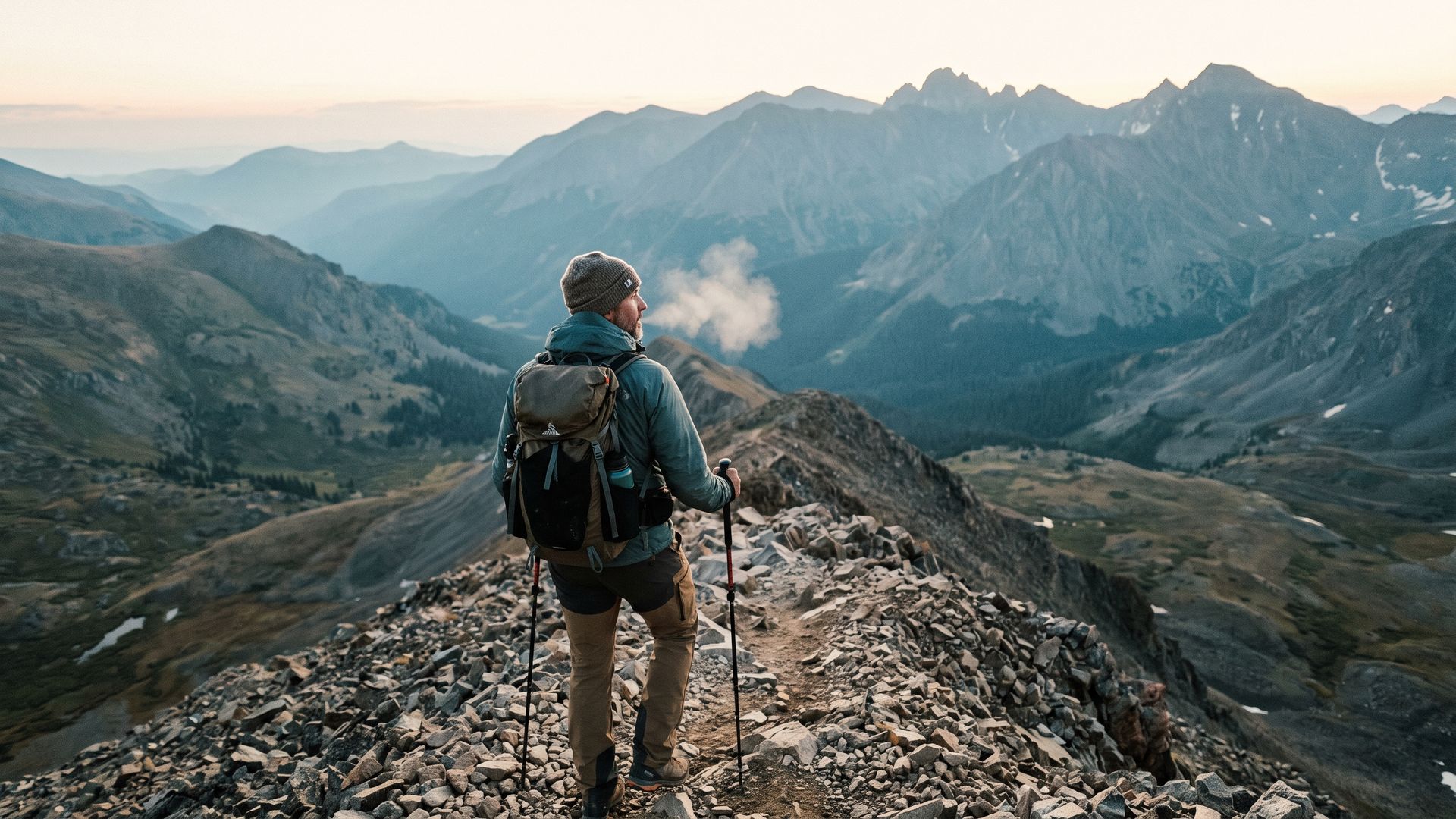 A man hiking a steep rocky ridge on a Colorado fourteener at dawn