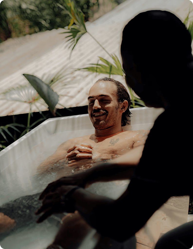 A man relaxing in a cold plunge surrounded by tropical greenery at the KORU Retreat
